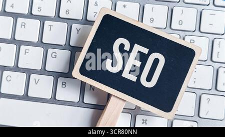 Close-up of Chalkboard with Bold SEO Text Placed Directly on White Computer Keyboard Keys Stock Photo