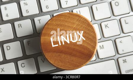 Close-up of Wooden Circle with LINUX Text Placed on Computer Keyboard Keys for Open-Source OS Concept Stock Photo