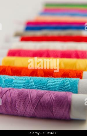 Brightly colored threads are neatly lined up, showcasing a variety of hues ideal for sewing and crafting. The vivid colors offer inspiration for creat Stock Photo