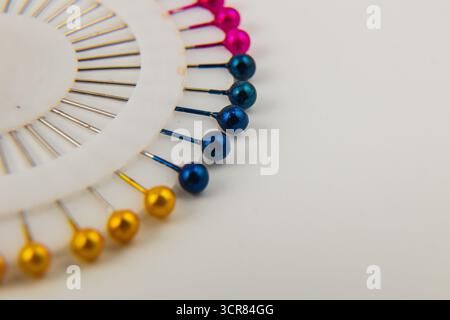 Brightly colored pins are displayed in a circular holder, showcasing shades of pink, blue, and gold. Ideal for sewing and crafting enthusiasts. Stock Photo
