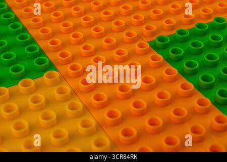 Brightly colored building blocks are arranged on a flat surface, showcasing vibrant orange, green, and yellow pieces in an engaging layout that invite Stock Photo