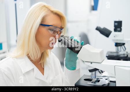 Scientists performing detailed medical research using a microscope in a modern laboratory setting.  Stock Photo