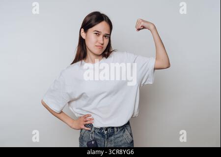 Strong young woman poses confidently while showing off her muscles in a casual indoor setting Stock Photo
