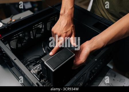 Close-up of technician hands installing CPU water cooler into desktop computer case, showcasing process of computer maintenance and upgrade. Stock Photo