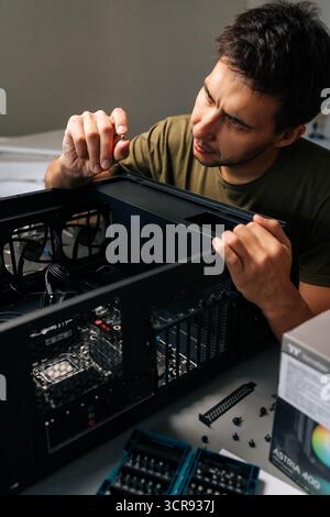 Vertical portrait of computer technician installing internal hardware components, precision-focused working inside desktop pc case, optimizing system Stock Photo