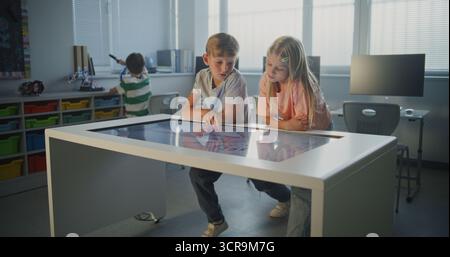 Schoolchildren Collaborate at Touchscreen, Examining Human Anatomy. Kids Talk, Actively Engage in Science Study. Concept of Modern Classroom Technology, Cooperative Biology Learning. Dolly Shot. Stock Photo