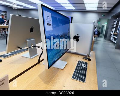 Manchester, UK - September 29, 2025: Bright tech space features multiple iMacs on wooden desks in a university or shop environment. Stock Photo