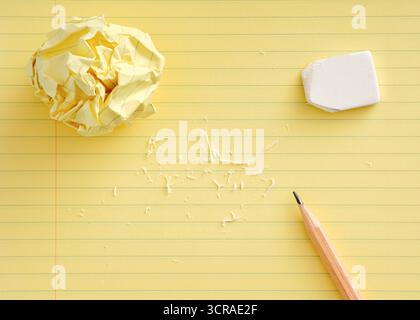 Brainstorming, editing or correcting a mistake concept featuring crumpled paper, pencil and eraser on a yellow legal pad Stock Photo