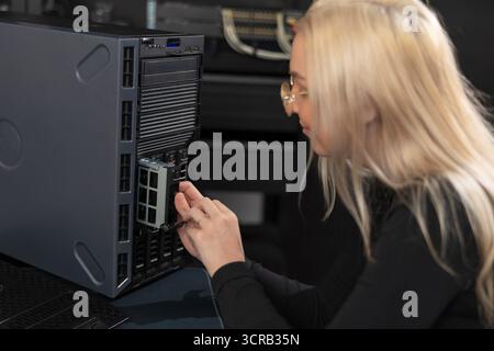 Female IT technician in their 20s working on a server rack in a data center Stock Photo