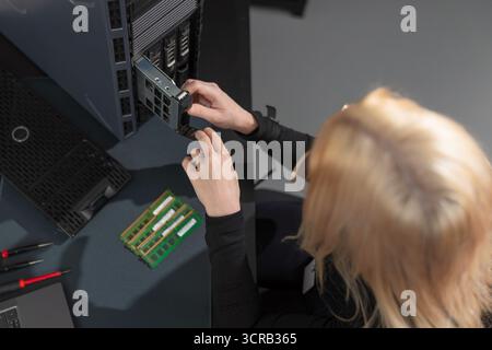 Female IT technician upgrades server hardware in a data center, focusing on maintenance and repair Stock Photo