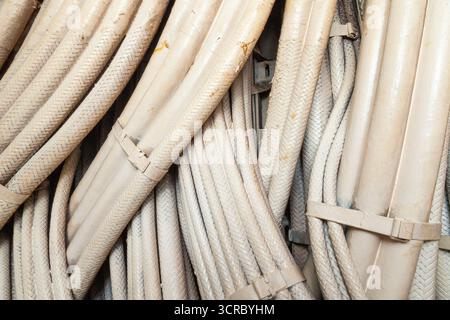 Bundle of many intertwined electrical cables in white protective sheath for power supply, close up Stock Photo