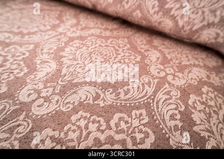 Detailed view of ornate damask fabric with floral and scroll motifs in soft tones Stock Photo