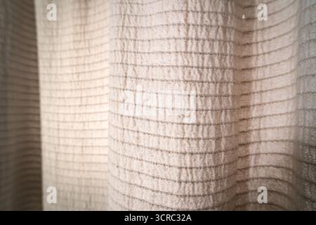 Detailed view of soft beige textile with subtle grid pattern and vertical draped folds Stock Photo