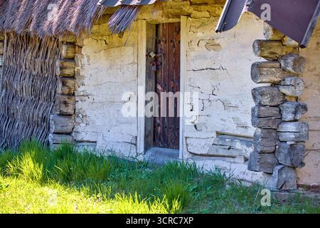 images of padlocks hanging on old wooden doors in a wall made of logs coated with white clay Stock Photo