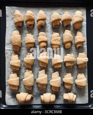 Croissants. Oven baked small croissants on a baking tray. Cornulețe, traditional Romanian dessert. Overhead view. Stock Photo