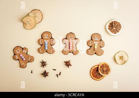 Homemade gingerbread cookies shaped like men with dried fruits and spices on beige background. Top view, flat lay. Stock Photo
