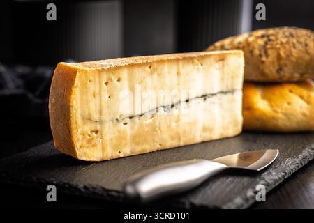 Morbier cheese. Delicious french cheese with mold on a black table. Stock Photo