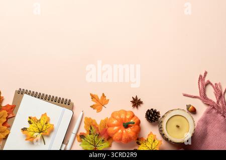 Autumn flat lay background. Autumn leaves, notepad, scarf, candle and spices on yellow background. Stock Photo