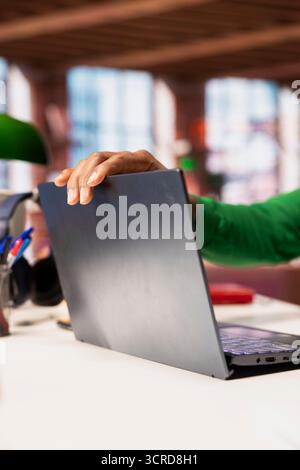 Remote employee at home office desk opening laptop lid to compose social media posts, producing content. Close up of remote worker starting job shift in the morning, monitoring social media engagement Stock Photo