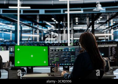 Engineer in data center using green screen computer to check equipment performance upgrading infrastructure. Worker doing maintenance on supercomputers in servers room using mockup PC Stock Photo