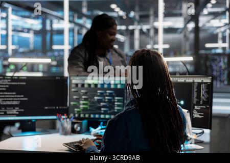 Data center system administrator using artificial intelligence neural networks tech and node trees. Server farm employee using AI programming language on computer, configuring specialized hardware Stock Photo