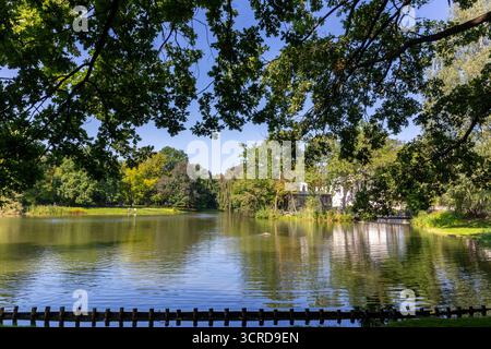 Warsaw's Royal Baths Park (Lazienki Krolewskie), landscape view with the lake, tree branches and leaves, reflections in the water, Poland. Stock Photo