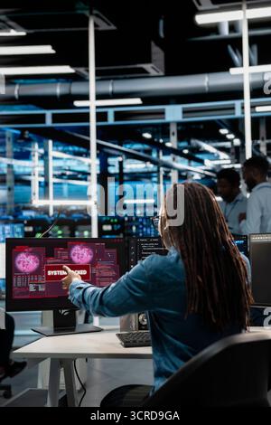 System administrator in server hub trying to protect hardware from hacker attack stealing sensitive information. Data center cybersecurity specialist fighting virus during security breach Stock Photo