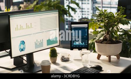 Business graphs and KPI metrics on displays in workplace, jib up shot. Office desk setup in bright corporate environment with computer screens displaying data analytics, close up shot Stock Photo