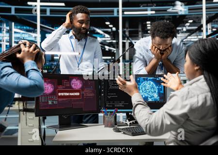 Data center technicians using artificial intelligence computerized model panicking after virus attack warning. Server room coworkers scared by hacking attempt on systems while using AI algorithms Stock Photo