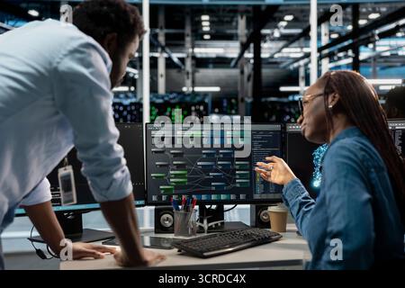 Manager supervising technician programming in server farm housing infrastructure storing datasets. Team leader overseeing IT expert coding, repairing data center racks doing computational operations Stock Photo