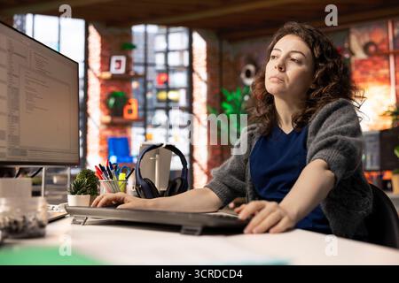Female programmer developing an app and software algorithm on pc, working at the creative agency. Engineer uses digital tools and focuses on java script engineering and coding, IT specialist. Stock Photo