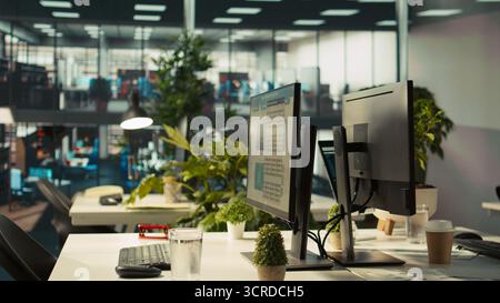 Business graphs and KPI metrics on displays in workplace, jib up shot. Office desk setup in bright corporate environment with computer screens displaying data analytics, close up shot Stock Photo
