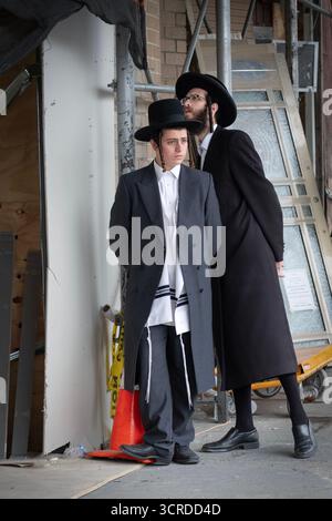 2 Hasidic Jewish men at a construction site but looking in opposite directions. In Brooklyn, NY, 2025. Stock Photo