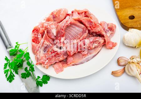 Chopped rabbit with garlic and spices on white plate with knife Stock Photo