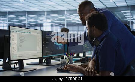 Manager assisting data center engineer in solving tasks, maintaining company network infrastructure. Team leader in server farm helping worker ensuring optimal system performance Stock Photo