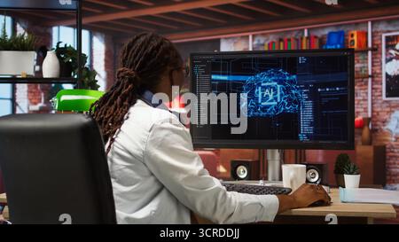 Freelancing computer engineer doing maintenance on artificial intelligence systems. Remote tech support specialist at working from home, doing checkup on AI systems, happy with results, camera A Stock Photo