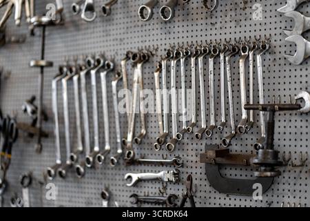 Various hand tools organized on pegboard in workshop. Screwdrivers, wrenches, and pliers neatly arranged for easy access, creating a functional workspace in garage Stock Photo