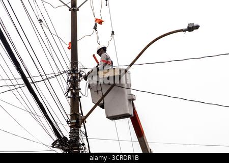 Marilia, SP, Brazil, September 22, 2025. Electrical technician performs maintenance on power lines using safety equipment and aerial lift platform, en Stock Photo