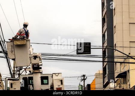 Marilia, SP, Brazil, September 22, 2025. Electrical technician performs maintenance on power lines using safety equipment and aerial lift platform, en Stock Photo