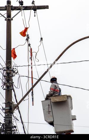Marilia, SP, Brazil, September 22, 2025. Electrical technician performs maintenance on power lines using safety equipment and aerial lift platform, en Stock Photo