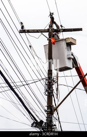 Marilia, SP, Brazil, September 22, 2025. Electrical technician performs maintenance on power lines using safety equipment and aerial lift platform, en Stock Photo