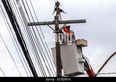 Marilia, SP, Brazil, September 22, 2025. Electrical technician performs maintenance on power lines using safety equipment and aerial lift platform, en Stock Photo