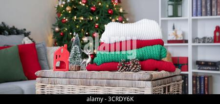 Stack of winter clothes with Christmas decorations on wicker basket at home Stock Photo