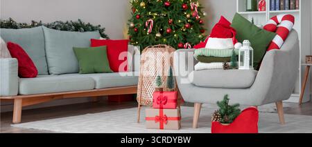 Stack of winter clothes with Christmas decorations and gifts on armchair at home Stock Photo