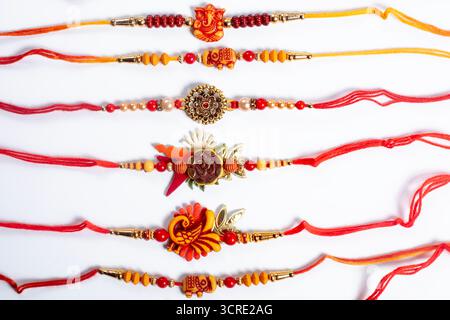 Six intricately designed Rakhi threads in bright colors on a white surface symbolize the celebration of the festival of Raksha Bandhan. Stock Photo