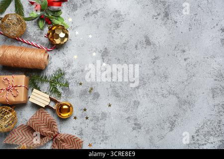 Composition with gift box, threads, Christmas decor and fir tree branches on grey grunge background Stock Photo