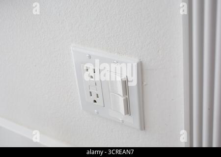 A view of a light switch and electrical outlet plate. Stock Photo