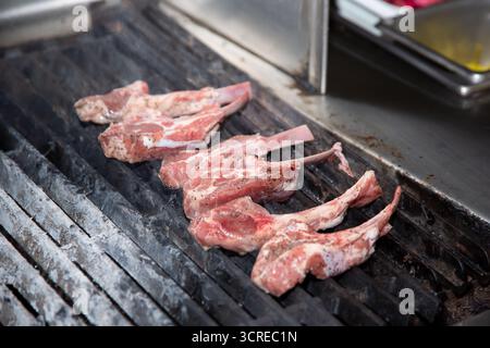 A view of raw lamb chops on the kitchen grill of a restaurant. Stock Photo
