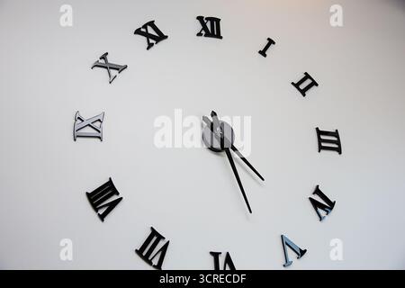 A view of a wall clock featuring Roman numerals. Stock Photo