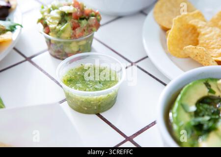 A view of a condiment cup of green salsa, or salsa verde. Stock Photo